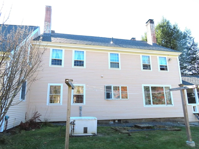 rear view of property featuring a lawn and a chimney