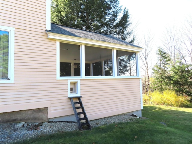 view of side of property featuring a sunroom, roof with shingles, and a yard