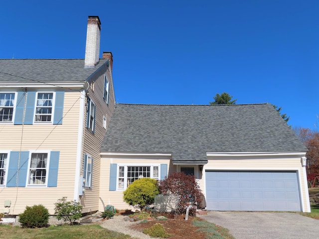 view of front facade with aphalt driveway, a chimney, an attached garage, and a shingled roof