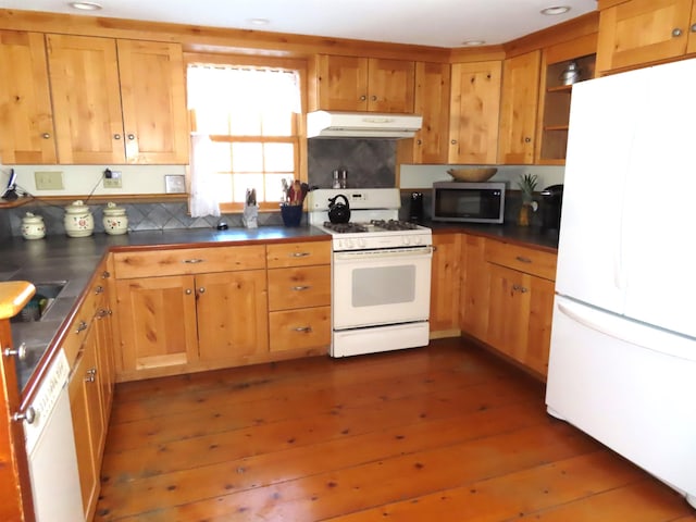 kitchen with dark countertops, white appliances, dark wood finished floors, and under cabinet range hood