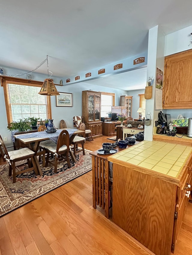 kitchen with light wood-style flooring, brown cabinetry, and tile counters