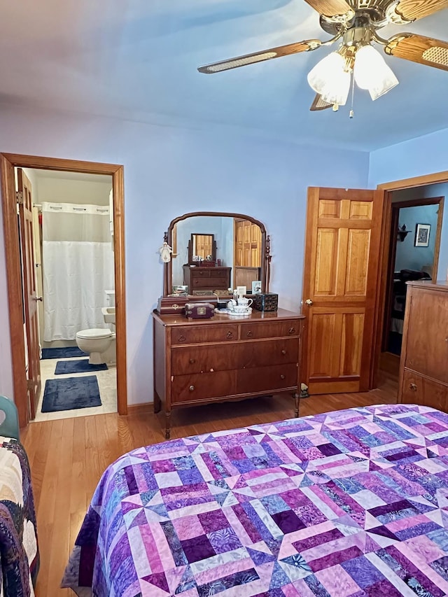 bedroom with ceiling fan, ensuite bath, and wood finished floors