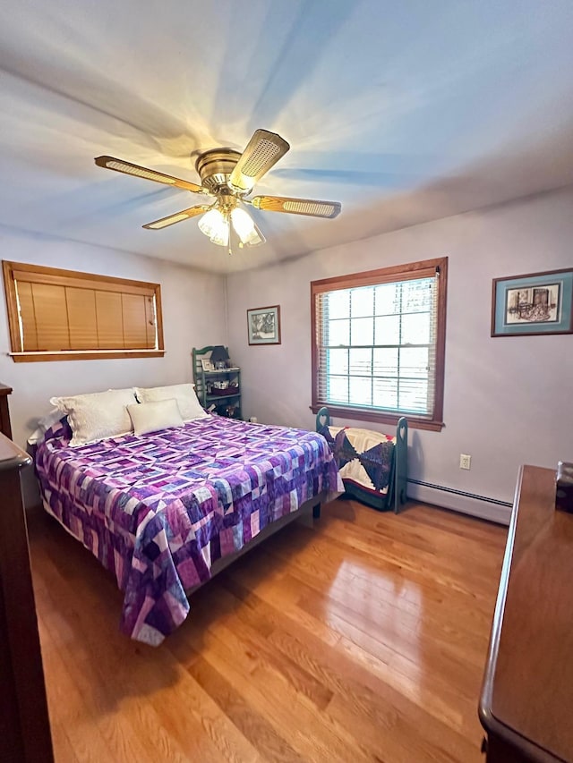 bedroom featuring a ceiling fan, baseboards, light wood finished floors, and baseboard heating