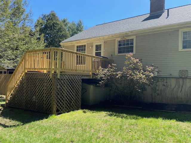 rear view of property featuring a shingled roof, a chimney, stairway, a deck, and a yard