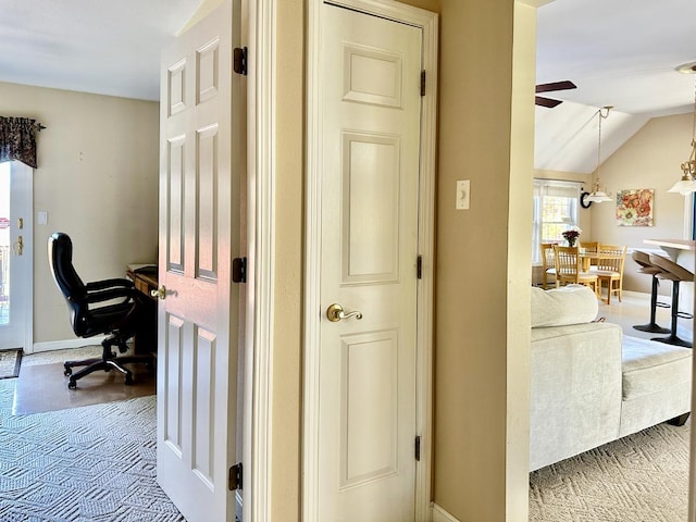 hall with lofted ceiling and baseboards