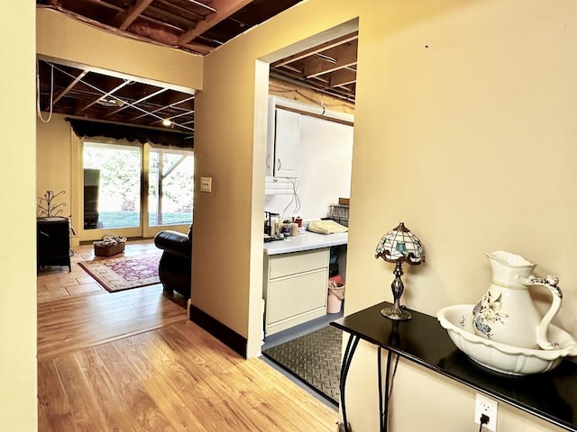 hallway featuring light wood-style flooring and baseboards