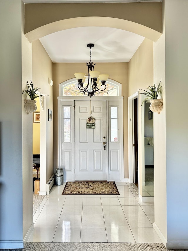 foyer entrance with arched walkways, light tile patterned floors, baseboards, and an inviting chandelier