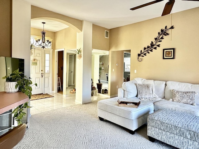 living room featuring arched walkways, light tile patterned floors, visible vents, baseboards, and ceiling fan with notable chandelier