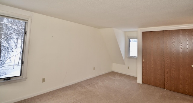 bonus room with a textured ceiling, carpet flooring, and baseboards