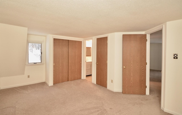 unfurnished bedroom featuring baseboards, a textured ceiling, and light colored carpet