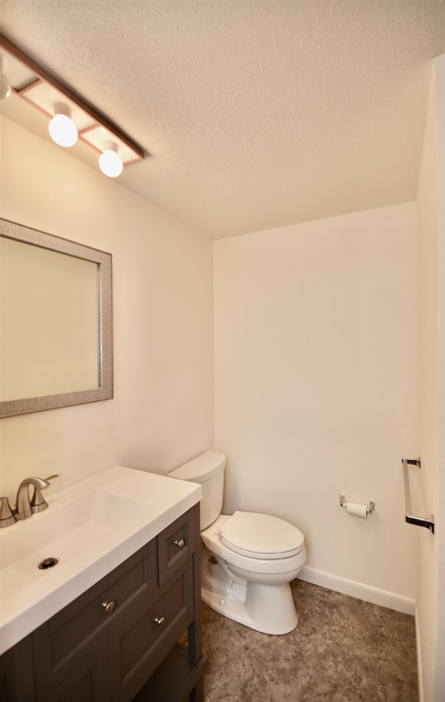 half bath with baseboards, vanity, toilet, and a textured ceiling