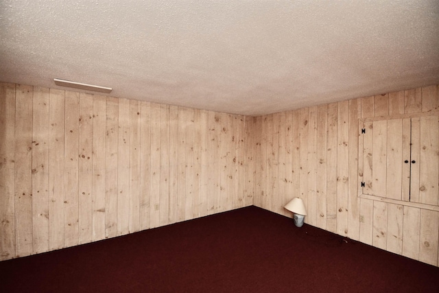 spare room with dark carpet and a textured ceiling