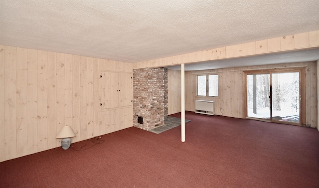 spare room featuring a textured ceiling, wood walls, and dark carpet