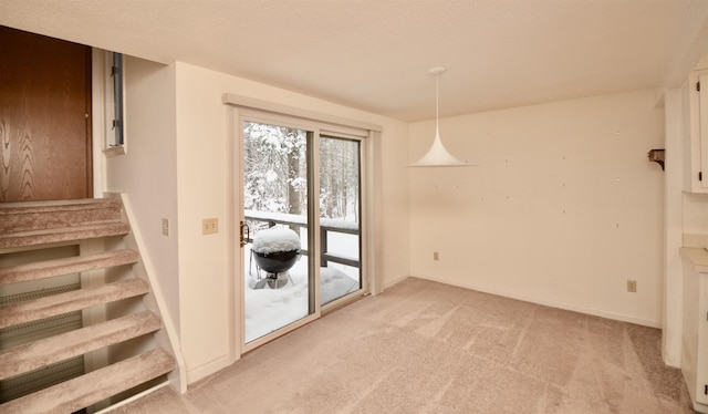 unfurnished dining area with light colored carpet, baseboards, and stairs