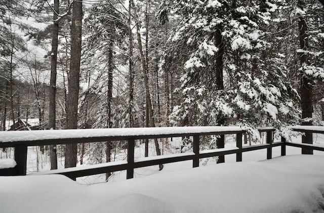 snow covered deck featuring a wooded view