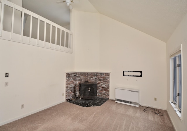 unfurnished living room featuring baseboards, a wood stove, heating unit, carpet, and high vaulted ceiling