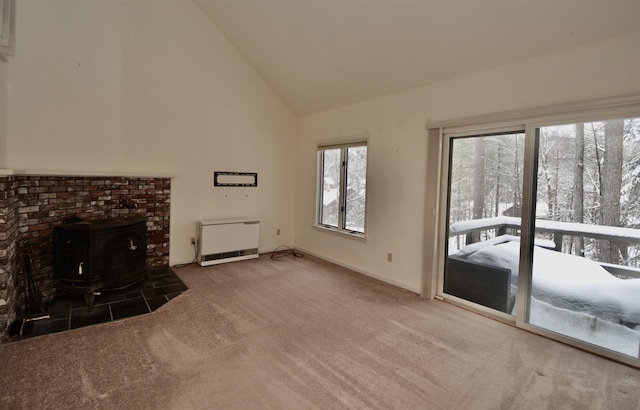 unfurnished living room featuring carpet floors, heating unit, a wood stove, high vaulted ceiling, and baseboards