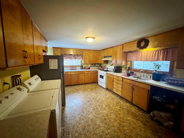 kitchen with white range with gas stovetop, light countertops, washer and dryer, under cabinet range hood, and a sink