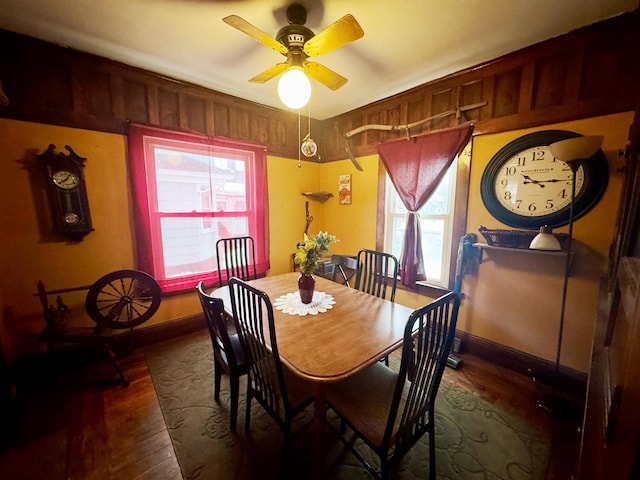 dining space with wood finished floors, a ceiling fan, and baseboards