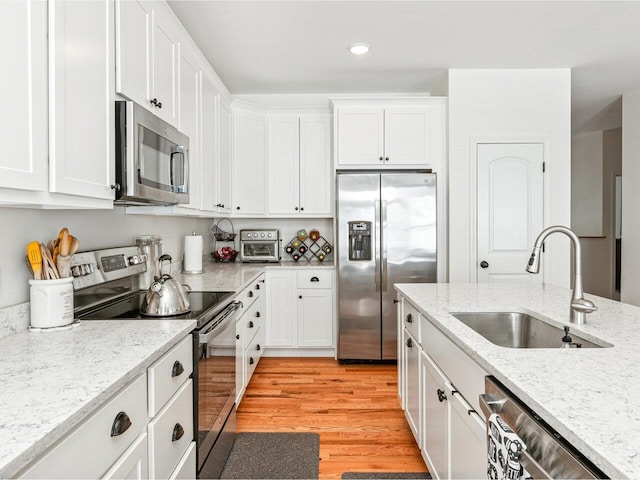 kitchen featuring light wood finished floors, white cabinetry, appliances with stainless steel finishes, and a sink