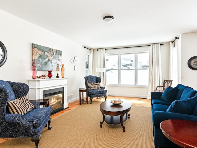 living room with a fireplace with flush hearth, baseboards, and wood finished floors