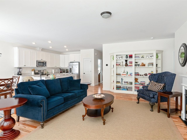 living room featuring light wood finished floors, baseboards, and recessed lighting