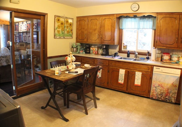 kitchen with brown cabinetry, light countertops, a sink, and dishwasher