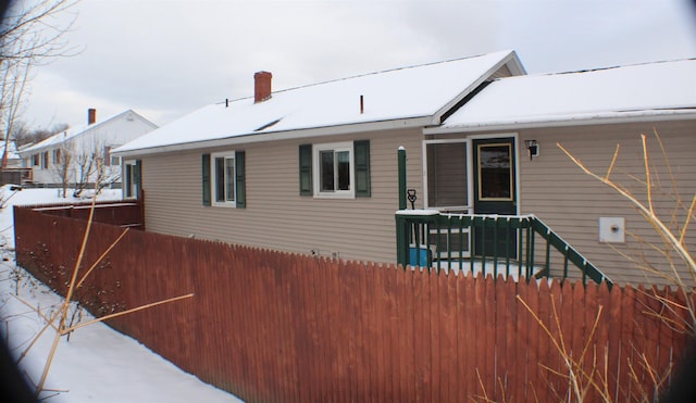 snow covered back of property featuring fence