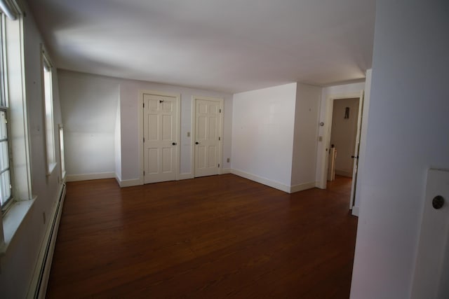 spare room featuring a baseboard radiator, baseboards, and wood finished floors