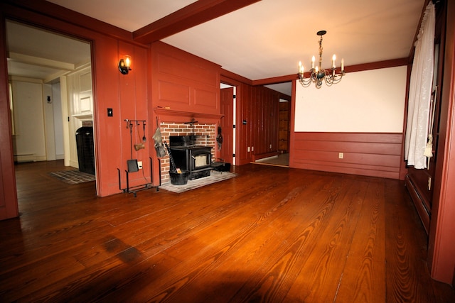 unfurnished living room with a baseboard radiator, a notable chandelier, wood finished floors, beamed ceiling, and a wood stove