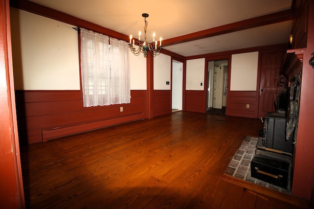 unfurnished dining area featuring a chandelier, wainscoting, baseboard heating, and wood finished floors