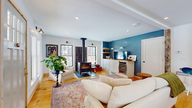 living area featuring a wood stove, light wood-style flooring, beverage cooler, and recessed lighting