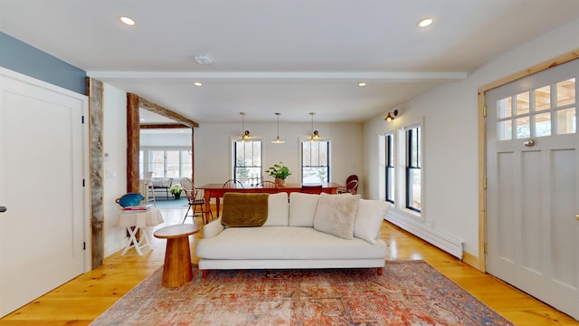 living area with light wood finished floors, a baseboard radiator, beam ceiling, and recessed lighting