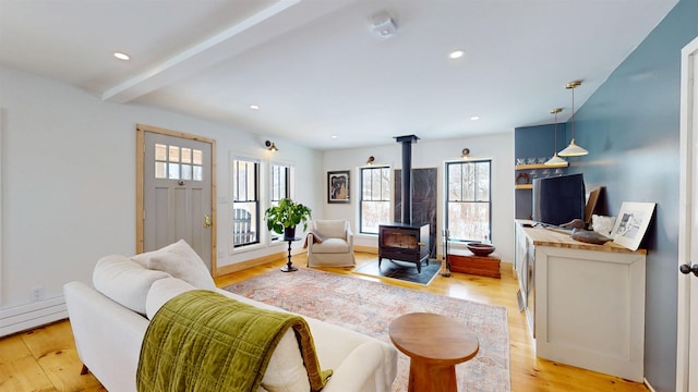 living room with recessed lighting, a wood stove, light wood-style flooring, and beam ceiling