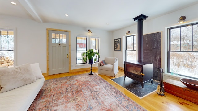 interior space with a wood stove, baseboards, wood finished floors, and recessed lighting