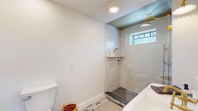 full bathroom featuring tile patterned flooring, toilet, a sink, baseboards, and a tile shower