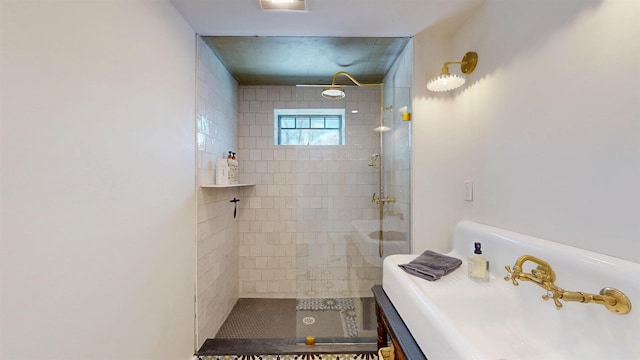 bathroom featuring tiled shower and a sink