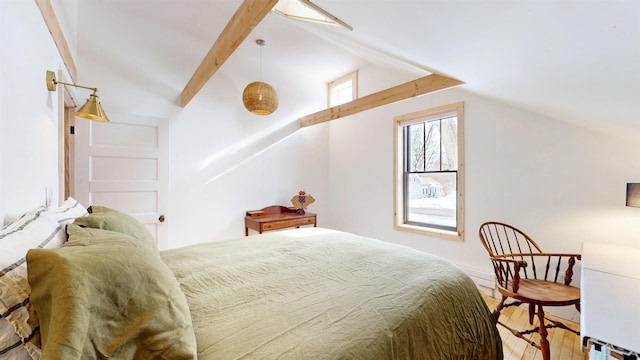 bedroom with lofted ceiling with beams and wood finished floors