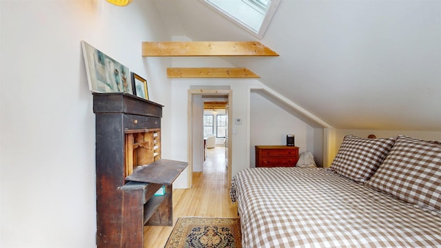 bedroom featuring vaulted ceiling with skylight and light wood finished floors