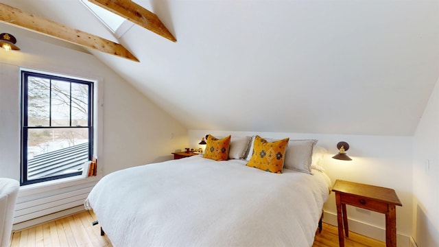 bedroom with lofted ceiling with skylight and light wood-type flooring