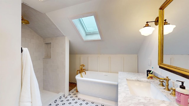 full bathroom featuring a soaking tub, tile patterned flooring, a tile shower, vanity, and vaulted ceiling with skylight