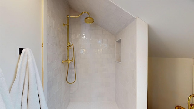 bathroom featuring lofted ceiling and tiled shower