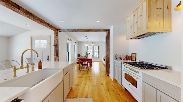 kitchen with recessed lighting, light countertops, light wood-style floors, a sink, and high end white range oven