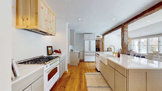 kitchen featuring white appliances, a sink, light countertops, beam ceiling, and light wood finished floors