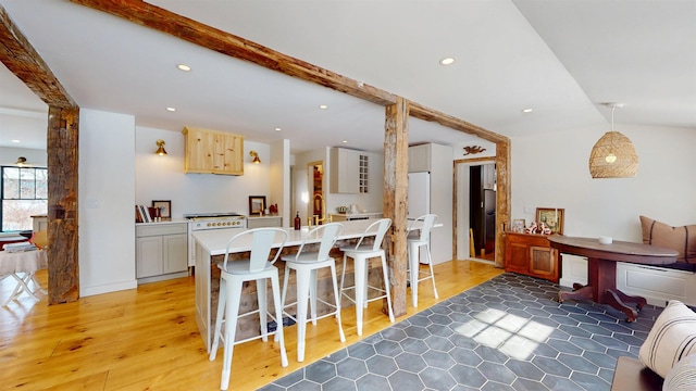 kitchen featuring a breakfast bar, light countertops, vaulted ceiling with beams, and recessed lighting