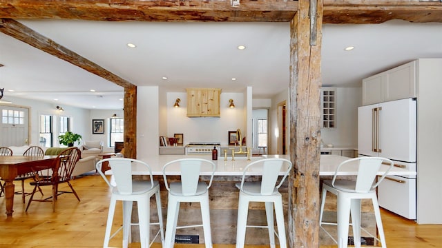 kitchen featuring light wood-type flooring, recessed lighting, a breakfast bar area, and high end white fridge