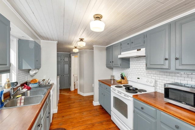 kitchen with under cabinet range hood, dark wood-style flooring, a sink, wooden counters, and white range with electric cooktop