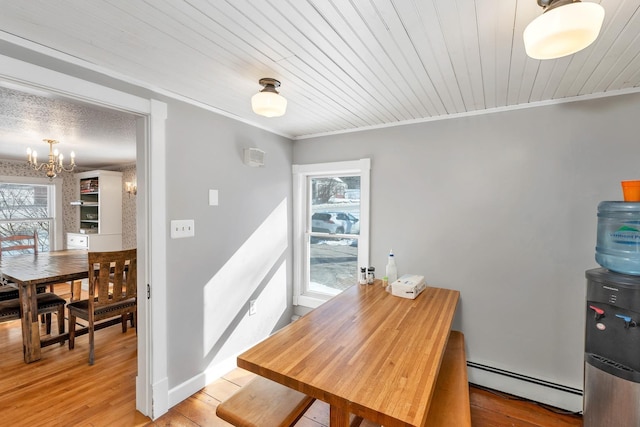 dining space with an inviting chandelier, light wood-style flooring, ornamental molding, and baseboard heating