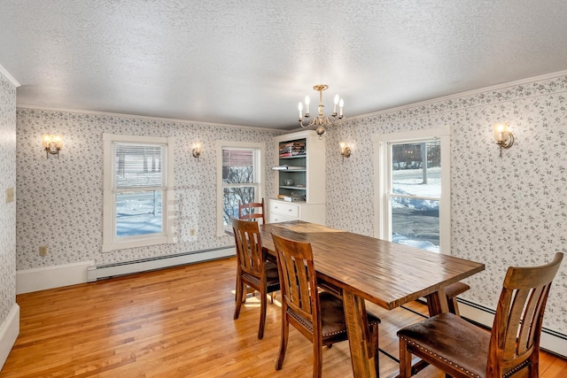 dining area with a textured ceiling, a baseboard radiator, light wood-type flooring, wallpapered walls, and crown molding