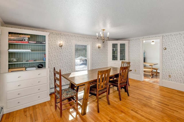 dining space featuring light wood-style flooring, a baseboard heating unit, a textured ceiling, a chandelier, and wallpapered walls